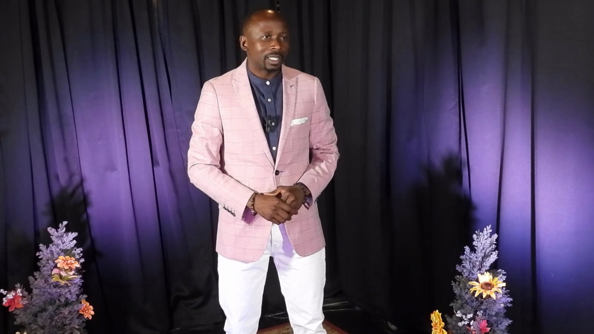 Amas on stage in pink blazer and white pants